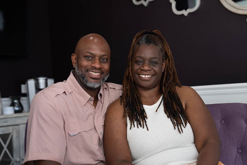 headshot of dental implant patient and their partner smiling brightly within the toothery